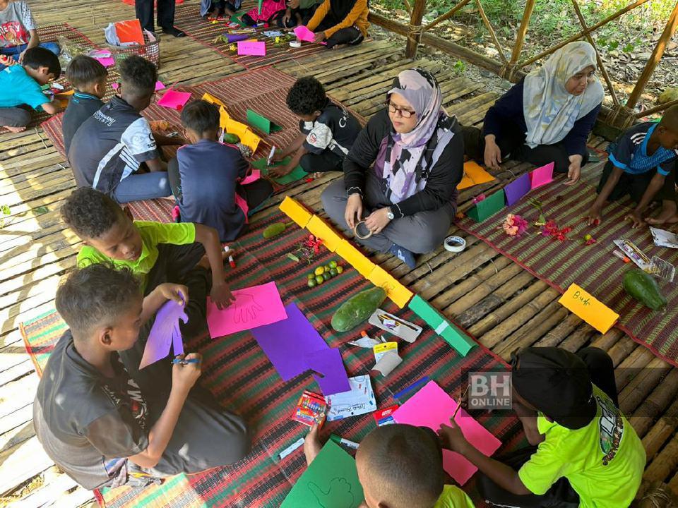 Fasilitator membantu kanak-kanak Orang Asli Semaq Beri ketika sesi pembelajaran di Sekolah Rimba. Gambar ihsan UMT